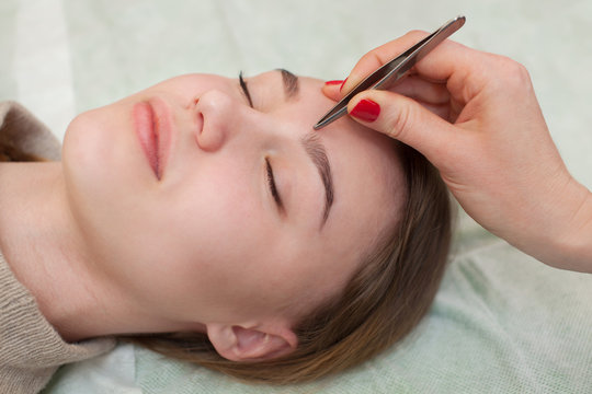 Master makeup corrects, and gives shape to pull out with forceps previously painted with henna eyebrows in a beauty salon. Professional care for face