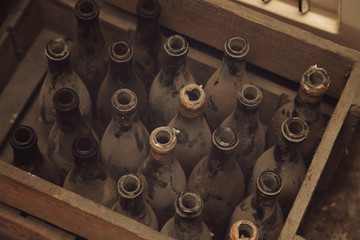 anciennes bouteilles de vin dans caisse en bois dans cave avec poussière