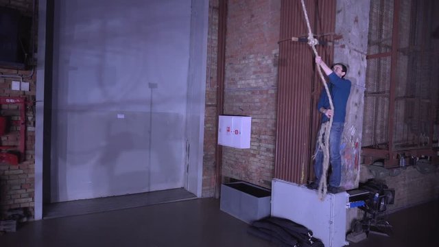 Man swings on a rope swing indoor