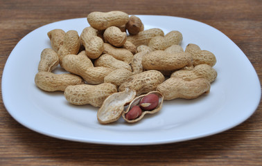 Nuts in a white plate on a wooden table