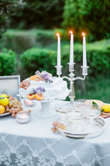 Wedding decor. Table setting with wedding cake, fruits,, cutlery, candle and dessert.