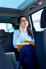 Beautiful young business woman in the car talking on phone.