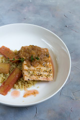 Grilled salmon with quinoa and rhubarb sauce. Gray background, white plate. Isolated.