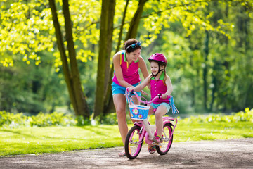 Obraz premium Mother teaching child to ride a bike
