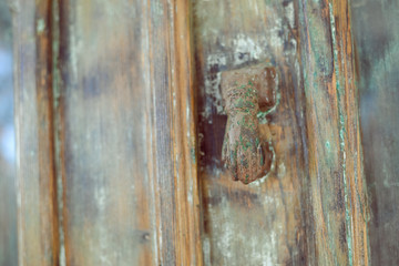 Closeup on old wooden entrance door with decorative antique door handle, selective focus, background blurry