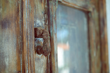 Closeup on old wooden entrance door with decorative antique door handle, selective focus, background blurry
