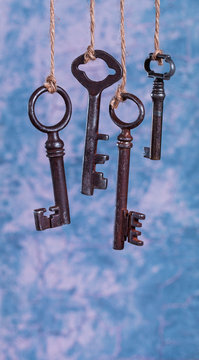 Four old rusty keys hanging on blue abstract background with copy space. Security concept