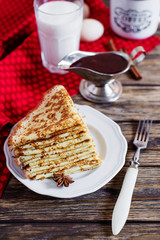 Delicious breakfast or dessert, pancakes with strawberry jam, cinnamon, milk and green tea on a dark rustic wooden background 