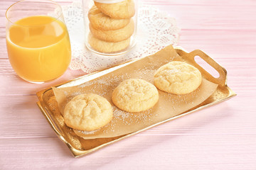 Tray with tasty sugar cookies and glass of juice on wooden background