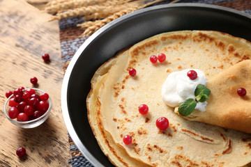 Pan with delicious pancakes and cranberry on table