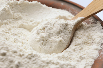 Fototapeta na wymiar Taking wheat flour from bowl, closeup