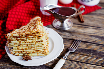 Delicious breakfast or dessert, pancakes with strawberry jam, cinnamon, milk and green tea on a dark rustic wooden background 