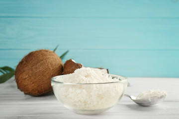 Glass bowl with coconut flakes on wooden table