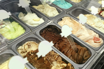 Showcase of different ice cream in metal tubs, closeup