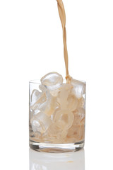 Irish creme liqueur pouring in a glass full of ice.