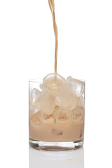 Irish creme liqueur pouring in a glass full of ice.