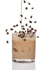 Coffee beans falling into cocktail and Irish creme liqueur pouring in a glass full of ice.