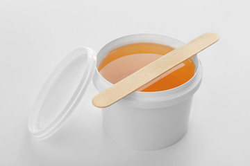 Plastic bucket with sugaring paste and stick on white background
