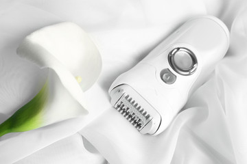 Modern epilator and flower on cloth