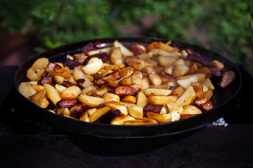 Beef meat stewed with potatoes on barbecue. Slice potatoes are prepared on the grill on sunny day. Close up. Culinary concept.