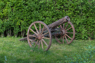 Fototapeta na wymiar Old wooden cannon gun with wheels on grass