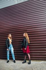 Two Women Talking in the City.Outdoor lifestyle portrait of two best friends hipster girls wearing stylish Leather Jacket and sunglasses, going crazy and having great time together