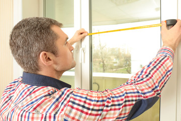 Young man installing window shades at home