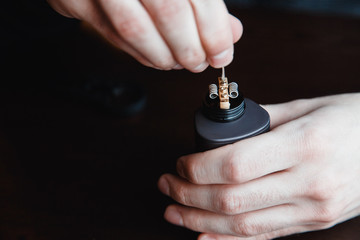male master installs a coil. Spiral for electronic evaporator and cigarette. Vape, vaping. Firing a coil. Burns, styling
