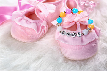 Bracelet with baby name Emma and booties on white fluffy background