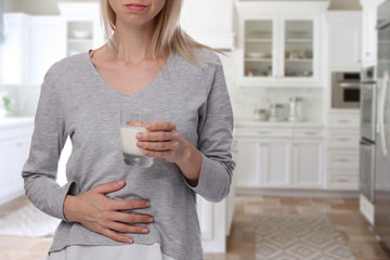Dairy Intolerant person.Woman with stomach pain holding a glass of milk. Lactose intolerance,...