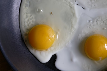 Fried eggs from a hen's egg in a frying pan with yellow yolks