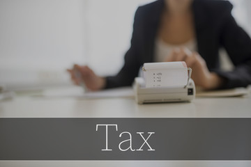 Tax text over adding machine with businesswoman