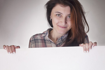 Happy beautiful Woman peeking behind a whiteboard