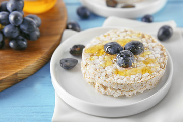 Tasty rice wafers with grape and honey on blue wooden table