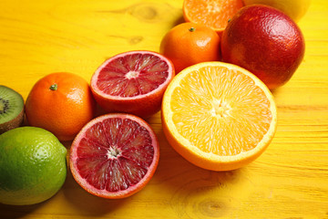 Fresh assorted citrus fruits on yellow wooden background