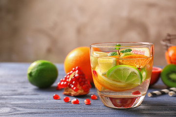 Glass with refreshing cocktail and citrus fruits on blue wooden table