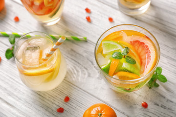 Glassware with refreshing citrus fruits cocktail on white wooden background