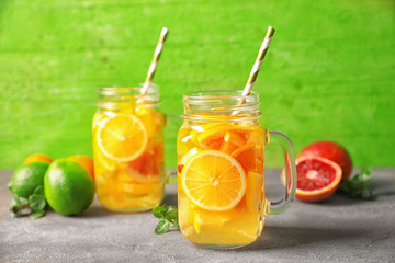 Glass mugs with refreshing citrus fruits cocktail on table