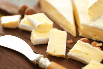 Sliced soft cheese and nuts on wooden board