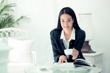 Young businesswoman sitting at table in coffee shop and reading book.