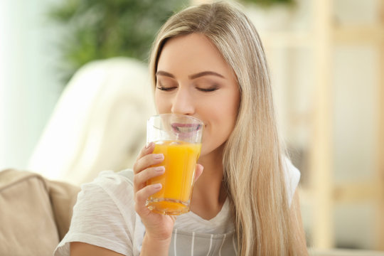 Beautiful young woman drinking fresh juice at home