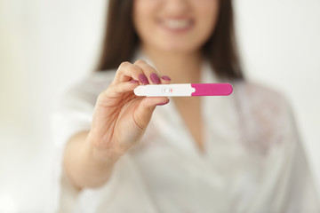 Pregnancy test in hand of young smiling woman