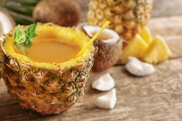 Cocktail in pineapple and coconut on wooden table