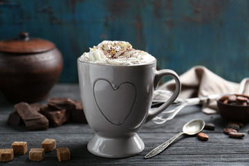 Cup of cocoa with whipped cream on wooden table