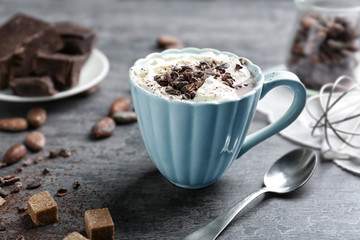 Cup of hot cocoa with whipped cream and chocolate on grunge kitchen table