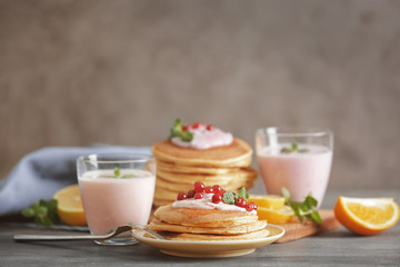 Delicious pancakes with yogurt and cranberry on table against blurred background