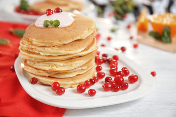 Plate with delicious pancakes, yogurt and cranberry on table