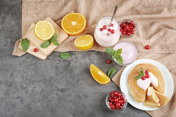 Composition of delicious pancakes with yogurt, berries and citrus fruits on table