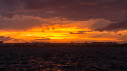 A brilliant orange sunset and crepuscular rays appears in the skies over the Potomac River as...