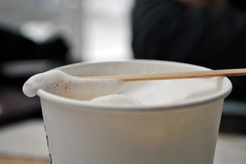 Close up of cappuccino foam on wooden stick; selective focus.